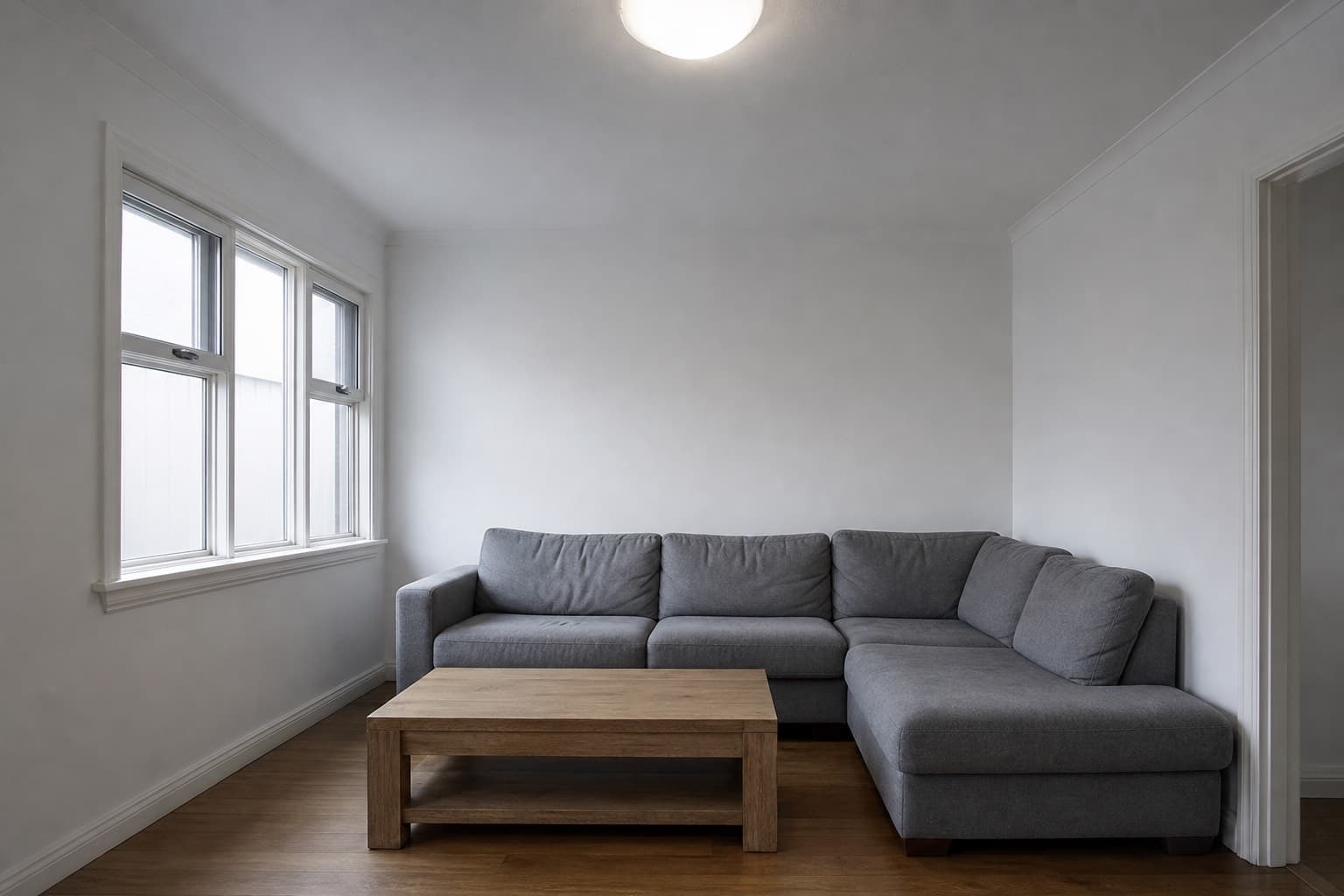 The same living room before styling, lit only by a flat ceiling light